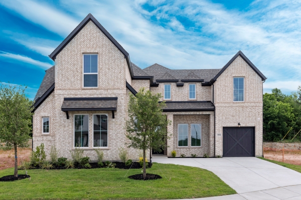 Front exterior of two-story brick home with gabled roof and single-car garage in Rockwall, TX