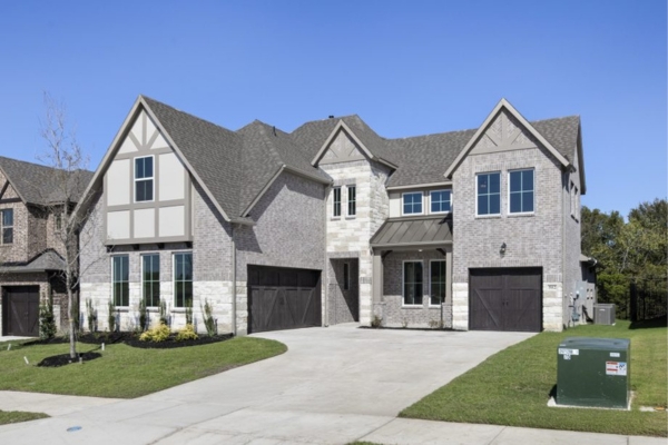 Exterior of the Preston floor plan home at 502 Shadow Ridge Road in Rockwall, TX featuring a two-story brick and stone façade with front-facing garages.