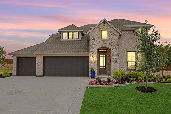 Model home exterior with stone and brick design at Timberbrook in Justin TX
